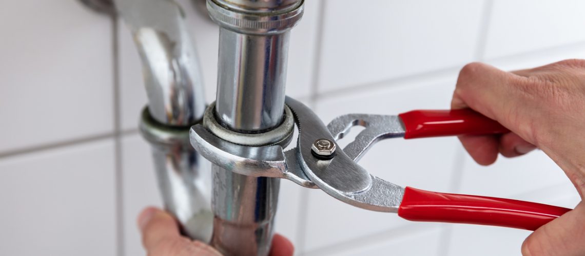 Close-up Of A Plumber's Hand Repairing Sink With Adjustable Wrench